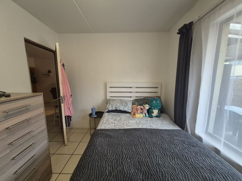 A functional bedroom featuring tiled flooring and large windows with curtain tracks, providing a neutral space ready for personalization.