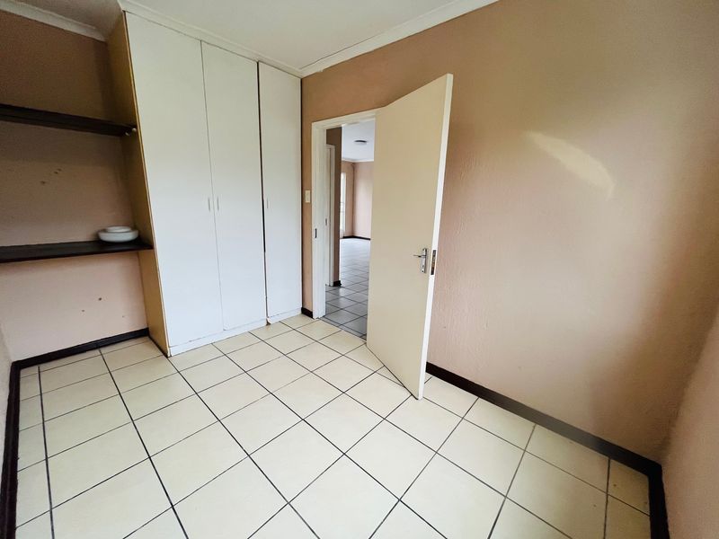 An empty bedroom featuring tiled flooring and built-in cupboards, offering a neutral canvas ready for personalization.