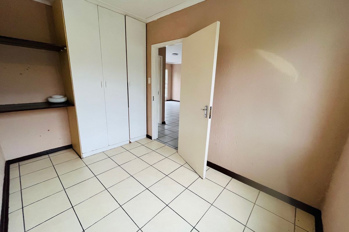 An empty bedroom featuring tiled flooring and built-in cupboards, offering a neutral canvas ready for personalization.