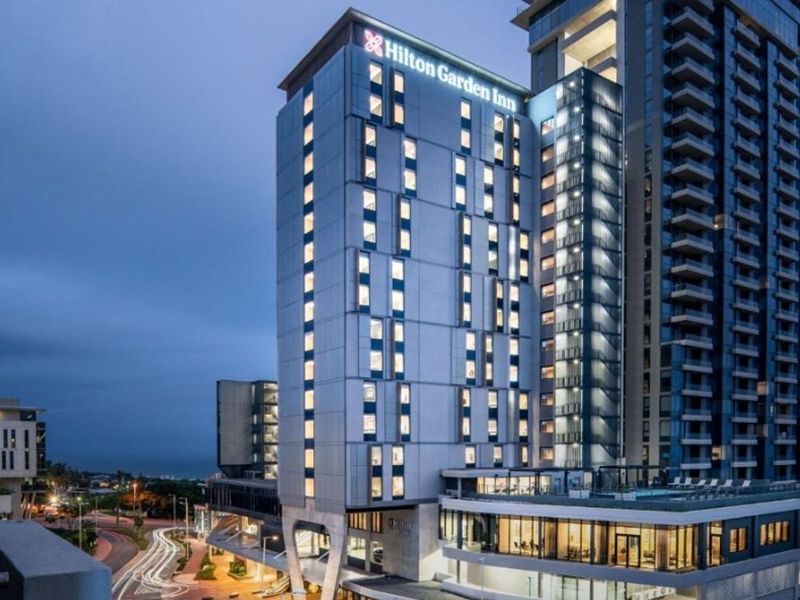 A professional exterior view of a modern multi-story hotel building featuring contemporary architectural design and illuminated facade at dusk.