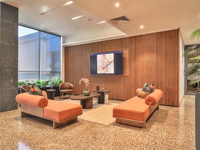A modern, well-appointed lounge area featuring elegant timber slat wall paneling, polished terrazzo flooring, and floor-to-ceiling windows providing ample natural light.
