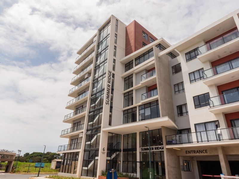Modern multi-story apartment building exterior featuring glass balconies, contemporary facade design, and a dedicated vehicle entrance.