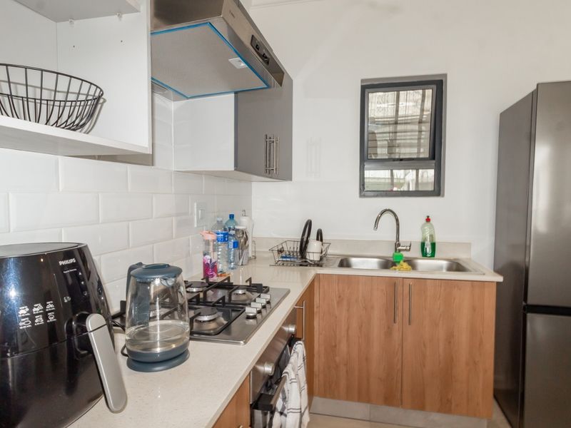Modern kitchen featuring a gas hob, extractor fan, built-in oven, double sink, and stylish subway tile backsplash with ample cabinetry.