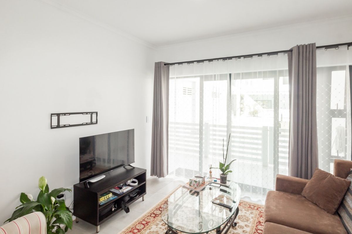 A bright living room featuring tiled flooring and a large sliding glass door that provides access to an outdoor area.