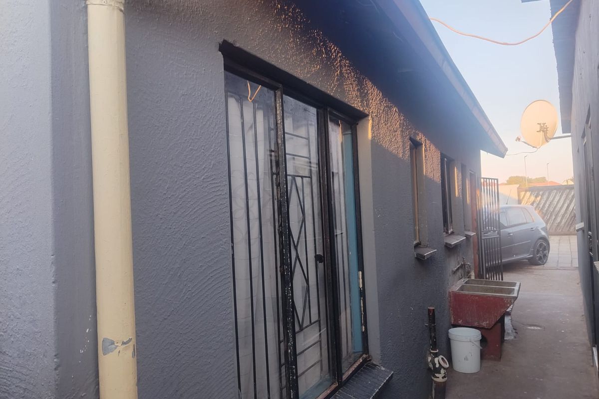 Side exterior view of the property featuring a concrete utility sink, security bars on windows, and a painted exterior wall.