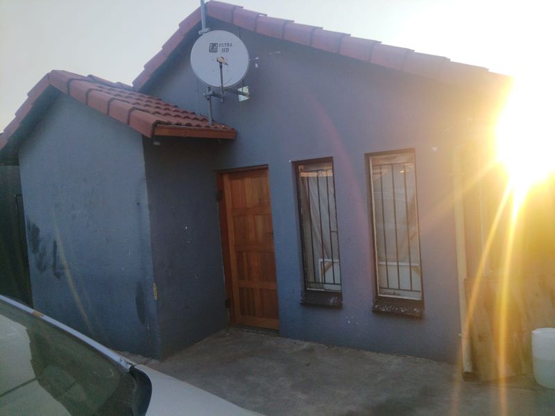 Front exterior view of a house featuring a tiled roof, timber entrance door, and security bars on the windows.