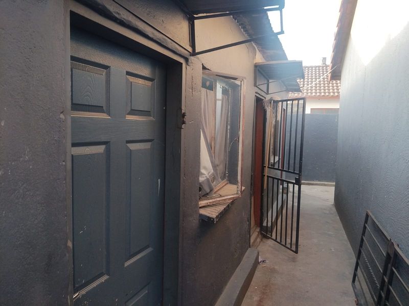 A narrow exterior side passage featuring a security gate, concrete pathway, and access to the rear of the property.