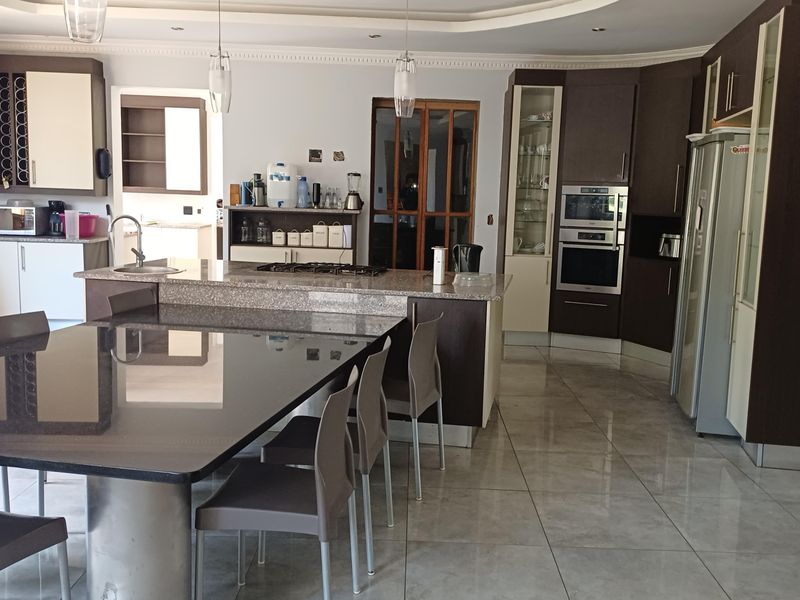 Spacious kitchen featuring granite countertops, built-in appliances, tiled flooring, and ample cabinetry, offering a functional and well-lit culinary workspace.
