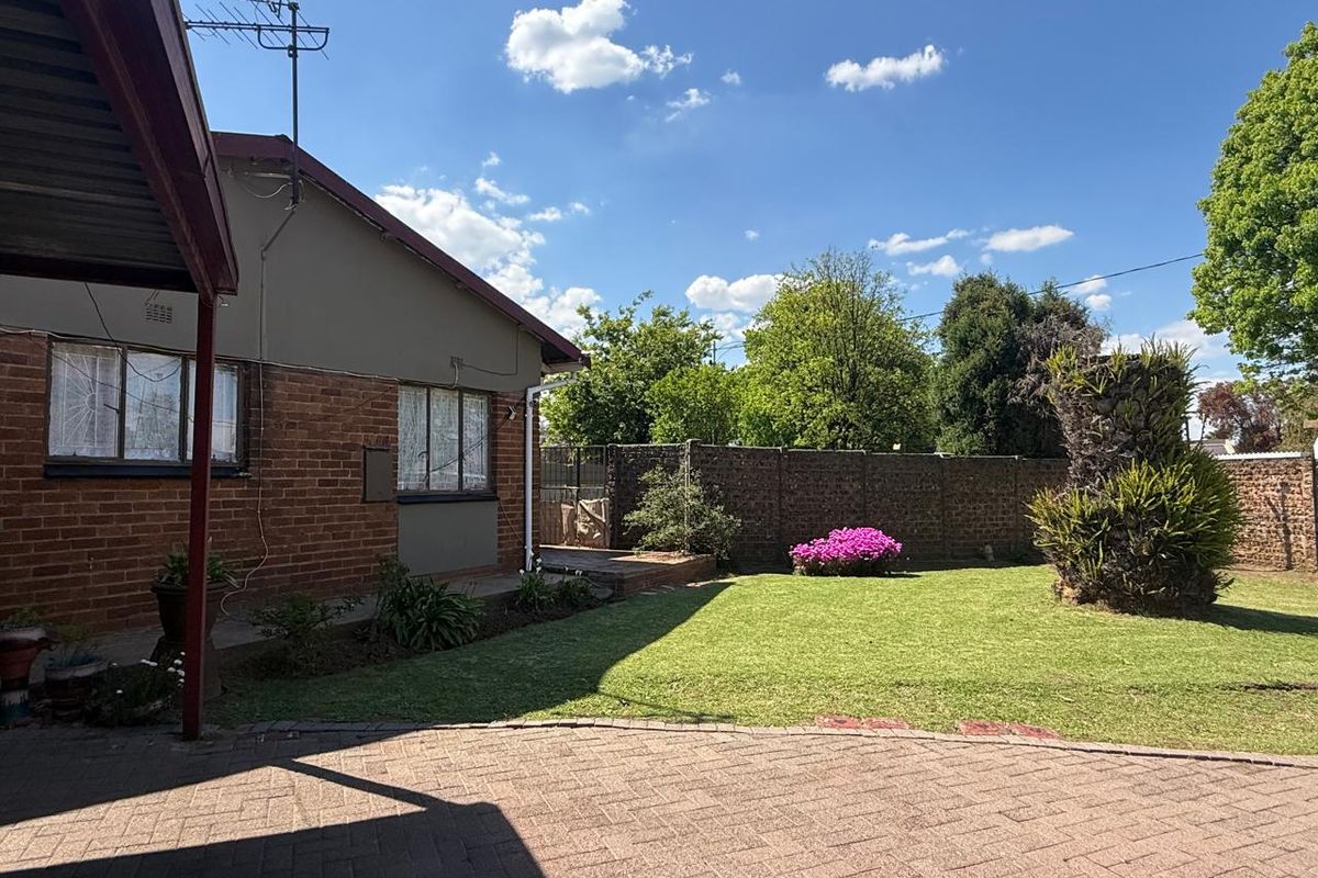 A well-maintained rear garden featuring a paved patio area, established lawn, and secure boundary walling, providing a private outdoor space.
