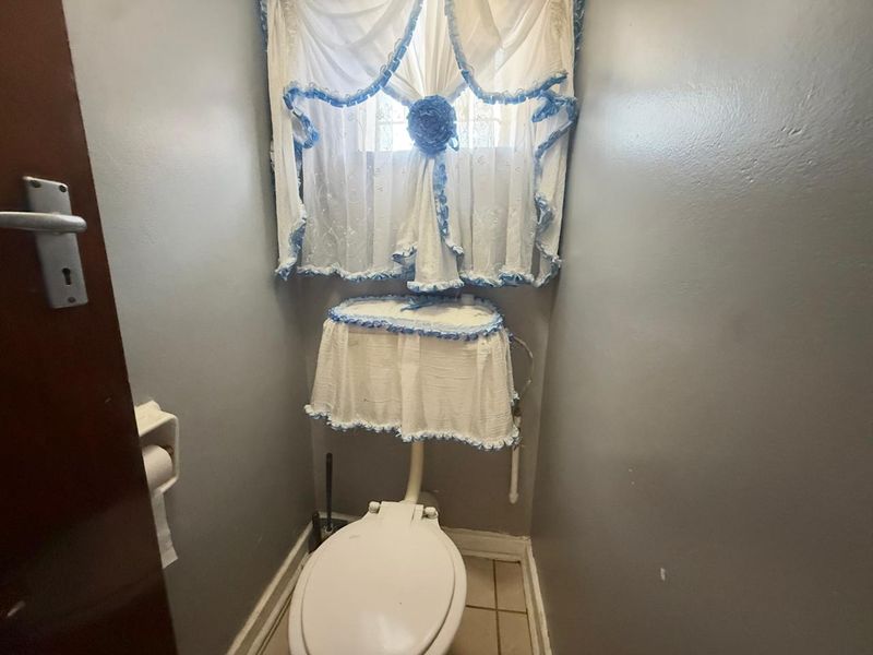 A compact bathroom featuring a standard toilet and tiled flooring, presenting a functional space ready for modern updates.
