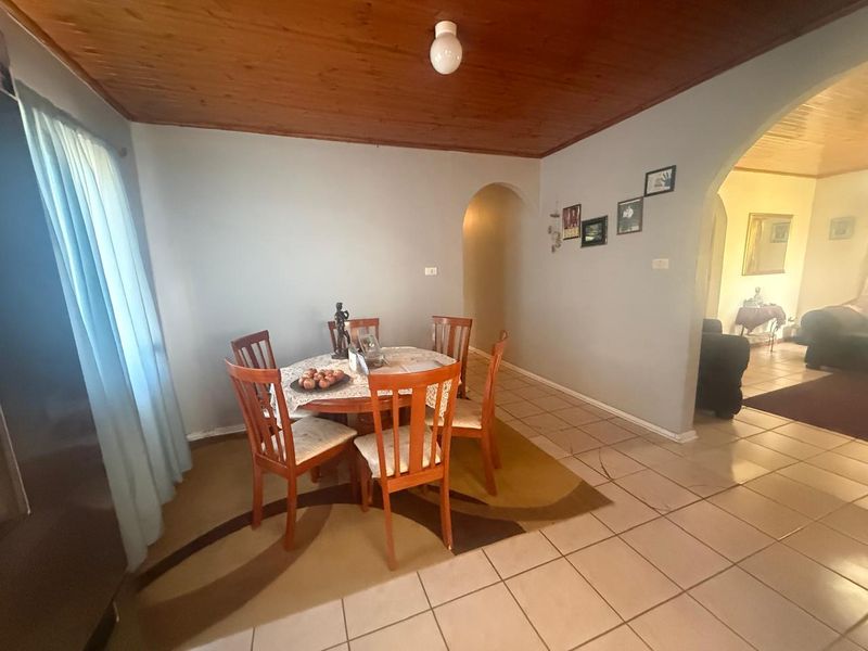 Dining area featuring ceramic floor tiles, a timber tongue and groove ceiling, and an arched doorway leading to adjacent living spaces.