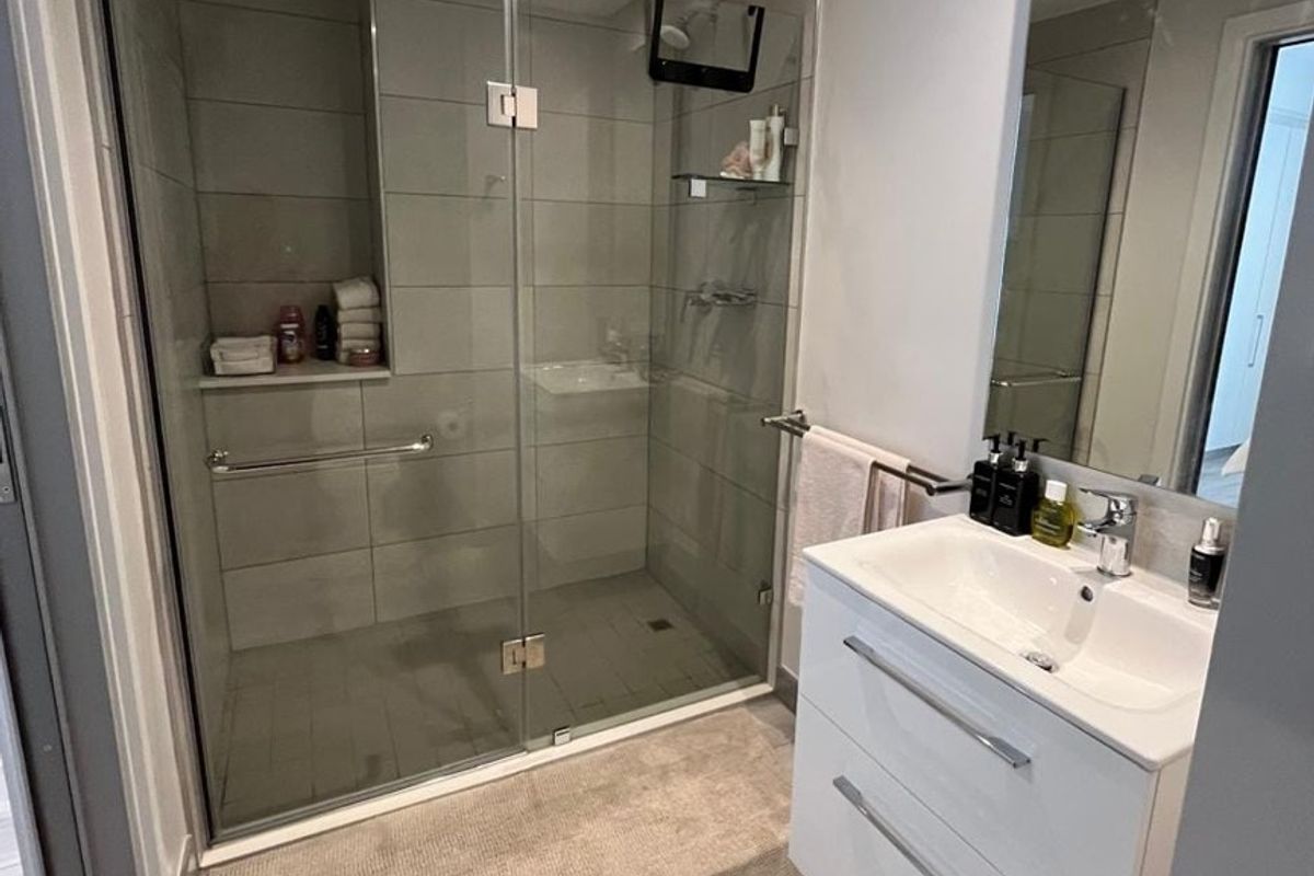 Modern bathroom featuring a spacious walk-in shower with glass enclosure, tiled finishes, and a contemporary wall-mounted vanity unit with a ceramic basin.