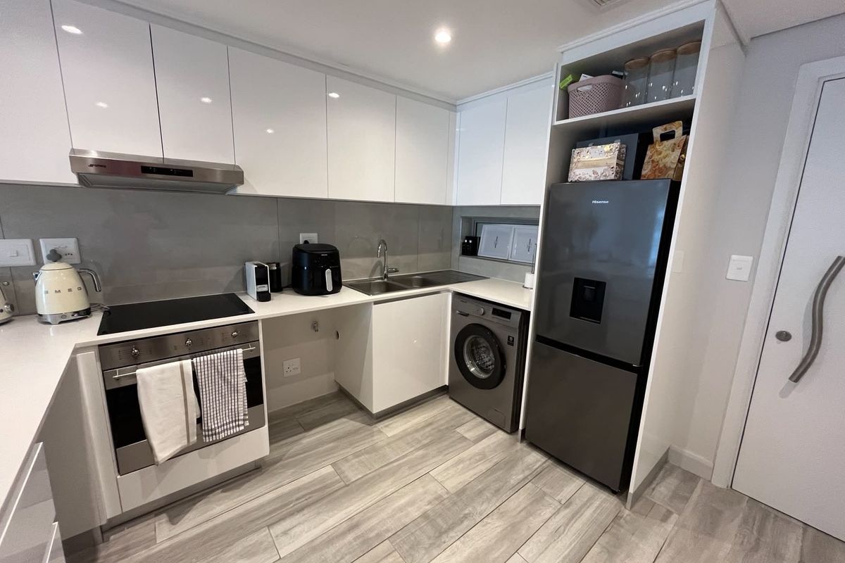 Modern kitchen featuring sleek white cabinetry, stone countertops, integrated appliances, and high-quality finishes throughout.
