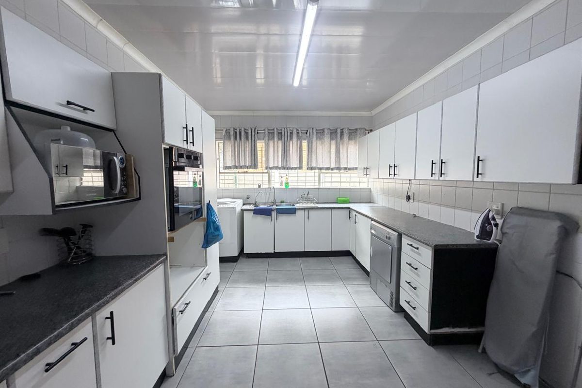 A functional kitchen featuring white cabinetry, laminate countertops, tiled flooring, and built-in oven, offering a clean and practical workspace.