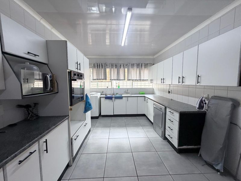 A functional kitchen featuring white cabinetry, laminate countertops, tiled flooring, and built-in oven, offering a clean and practical workspace.