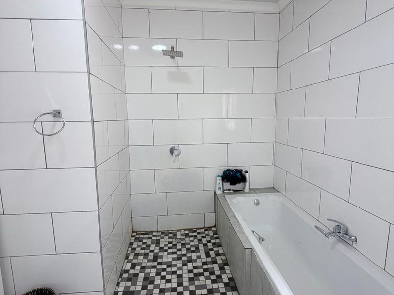 A modern bathroom featuring a built-in bathtub and a walk-in shower area with white subway wall tiles and a decorative mosaic floor pattern.