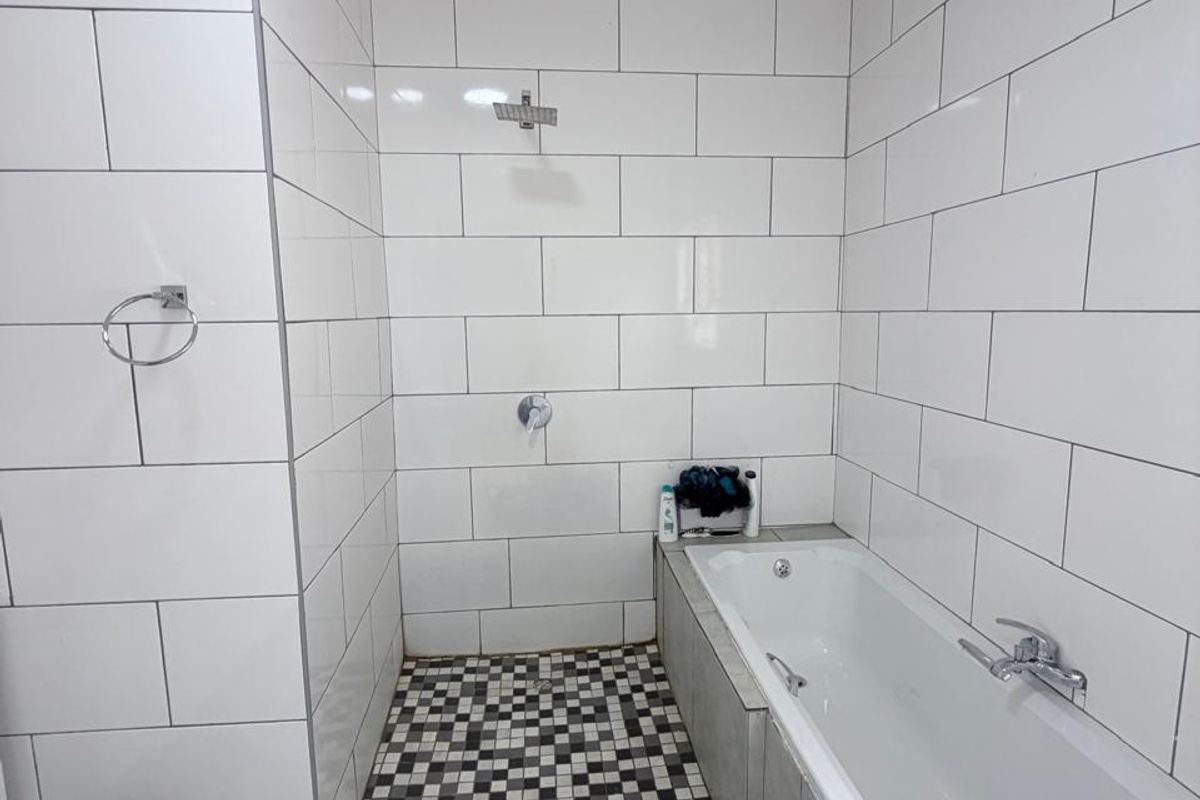 A modern bathroom featuring a built-in bathtub and a walk-in shower area with white subway wall tiles and a decorative mosaic floor pattern.