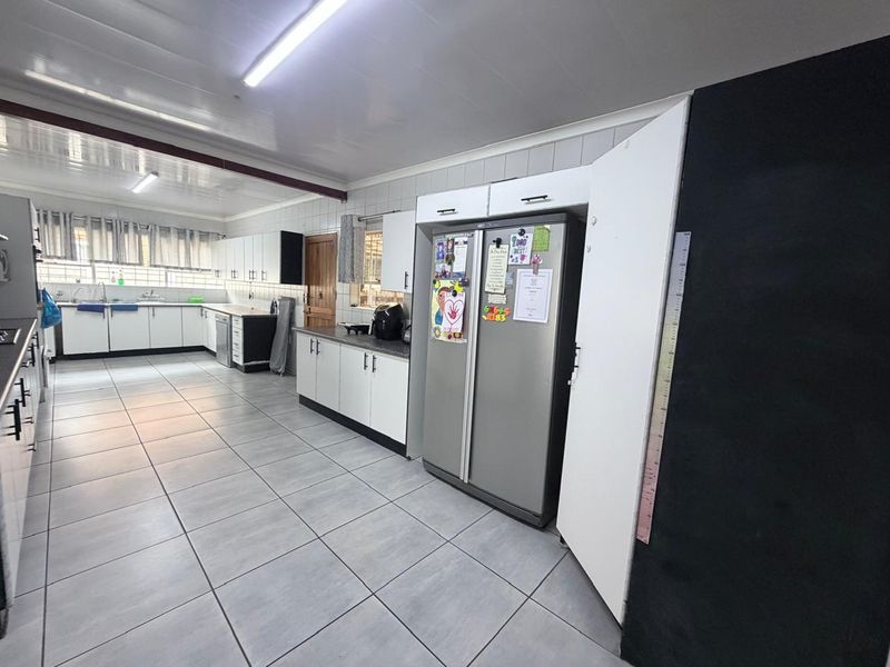 Spacious kitchen featuring extensive built-in cabinetry, tiled flooring, and a functional layout with ample counter space and a double sink.