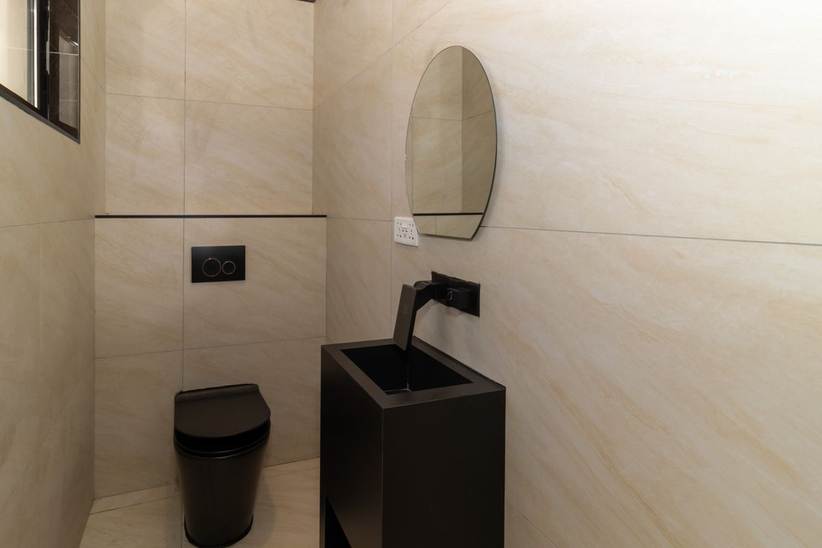 Modern guest bathroom featuring neutral wall tiles, a sleek black wall-mounted toilet with concealed cistern, and a contemporary black vanity basin.