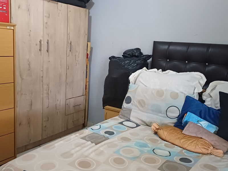 A bedroom featuring a built-in wardrobe with light wood-grain finish cabinetry.