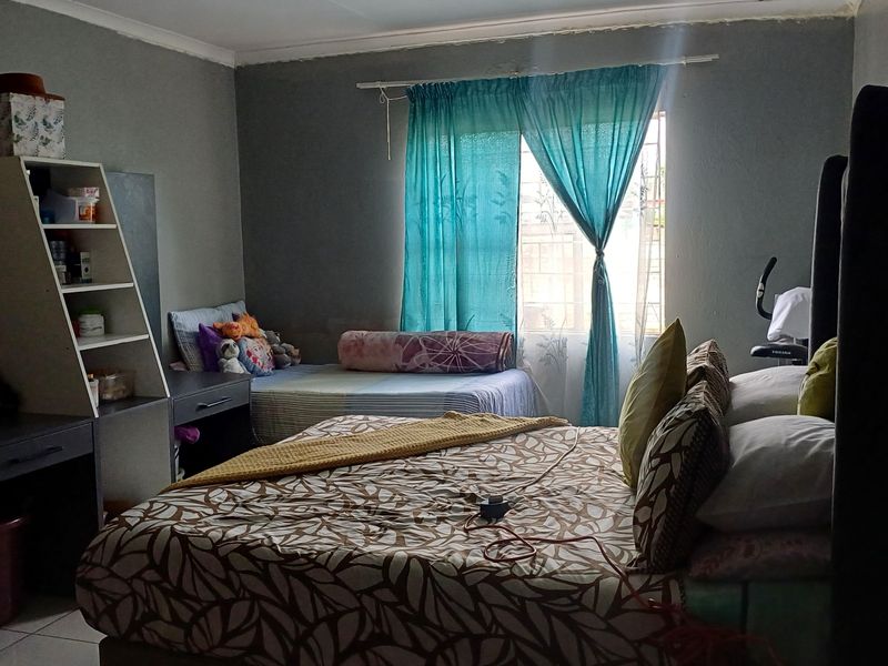 A bedroom featuring tiled flooring and a window with curtain rod, requiring minor cosmetic updates to the wall finishes.