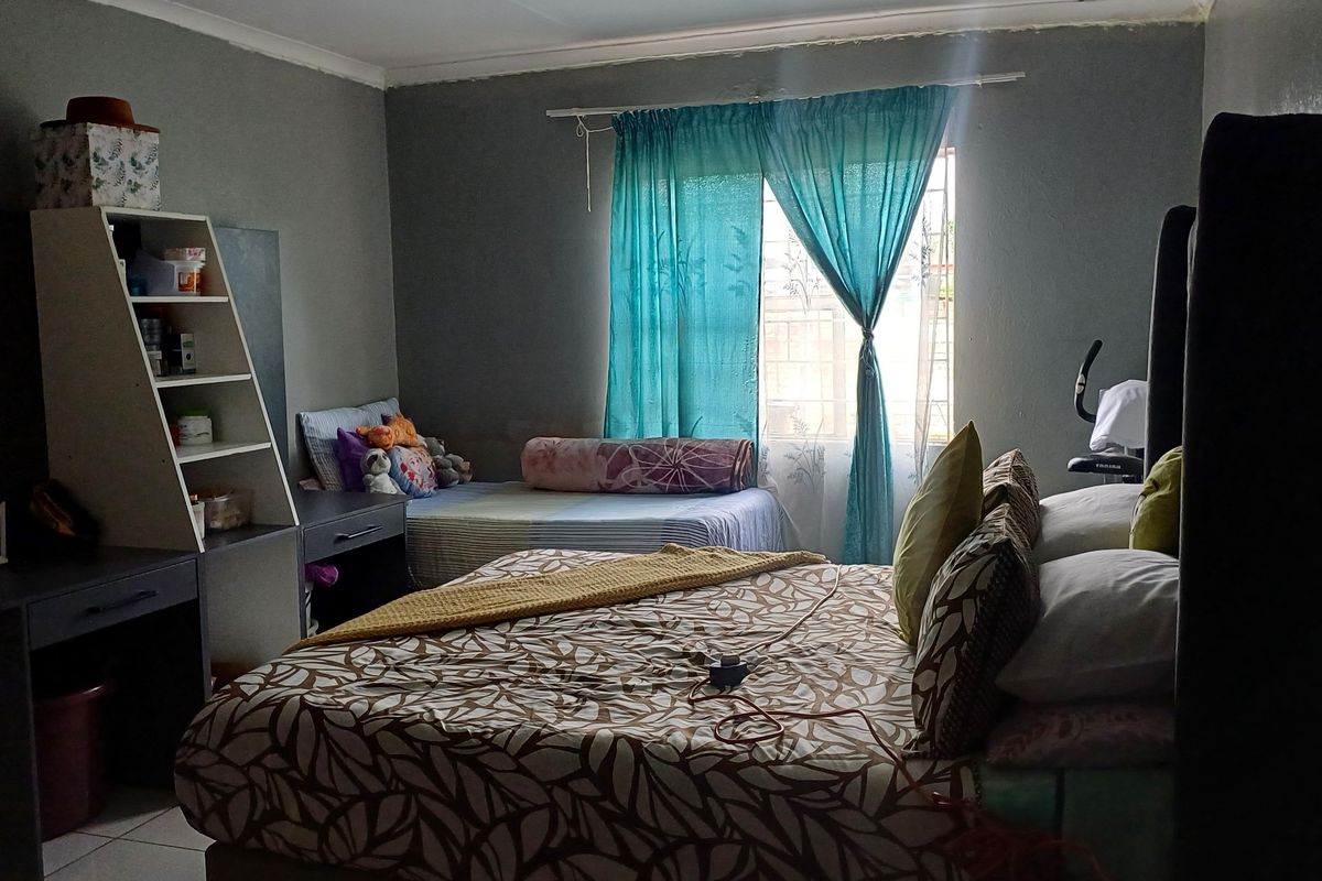 A bedroom featuring tiled flooring and a window with curtain rod, requiring minor cosmetic updates to the wall finishes.