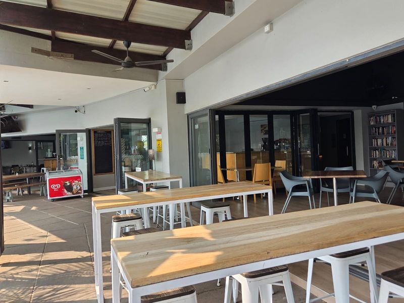 A spacious covered patio area featuring exposed timber beams, ceiling fans, and large bi-fold doors providing seamless indoor-outdoor flow.