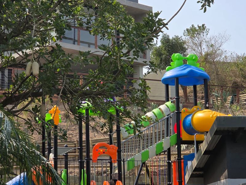 A tiered garden area featuring a retaining wall, metal fencing, and a multi-level landscape design with a playground structure.