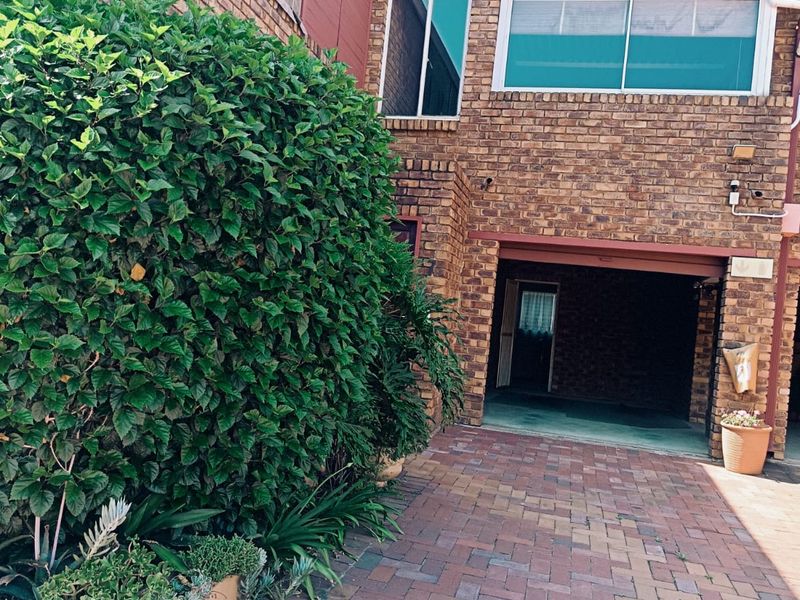 Front exterior view of a face brick apartment building featuring a paved driveway and a covered carport area.