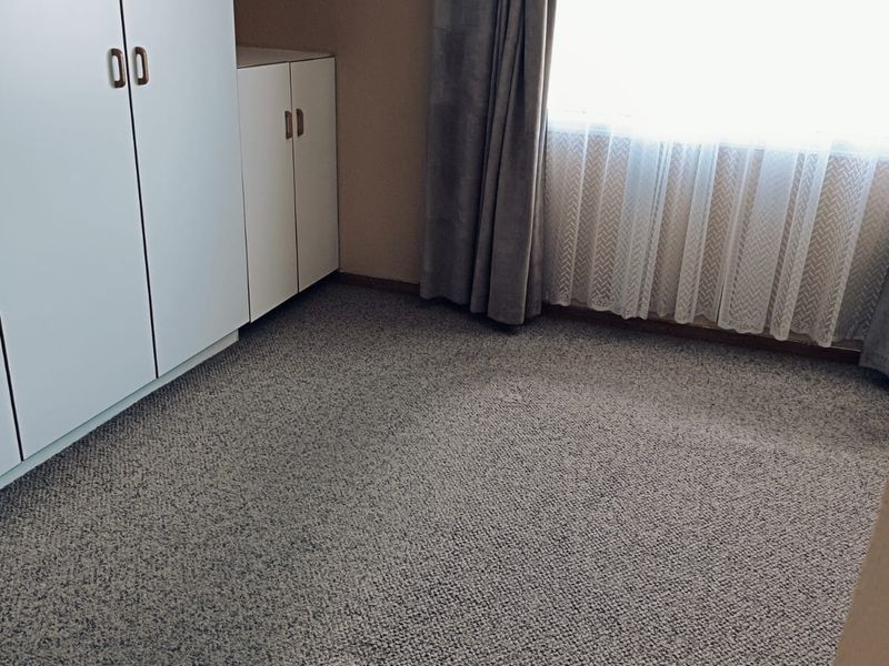 A clean, empty bedroom featuring neutral carpeting and built-in storage cupboards, offering a blank canvas for personalization.