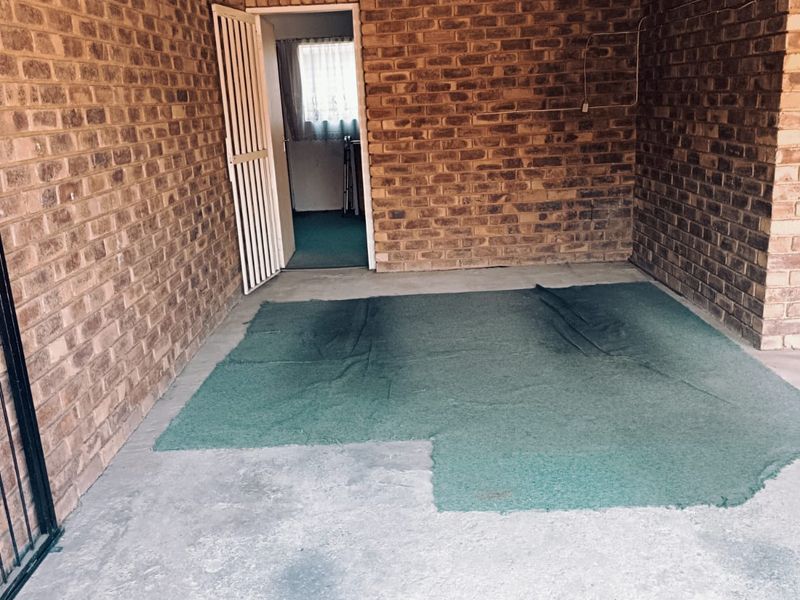 A functional garage space featuring exposed brick walls and concrete flooring, providing a secure area for vehicle storage or utility use.