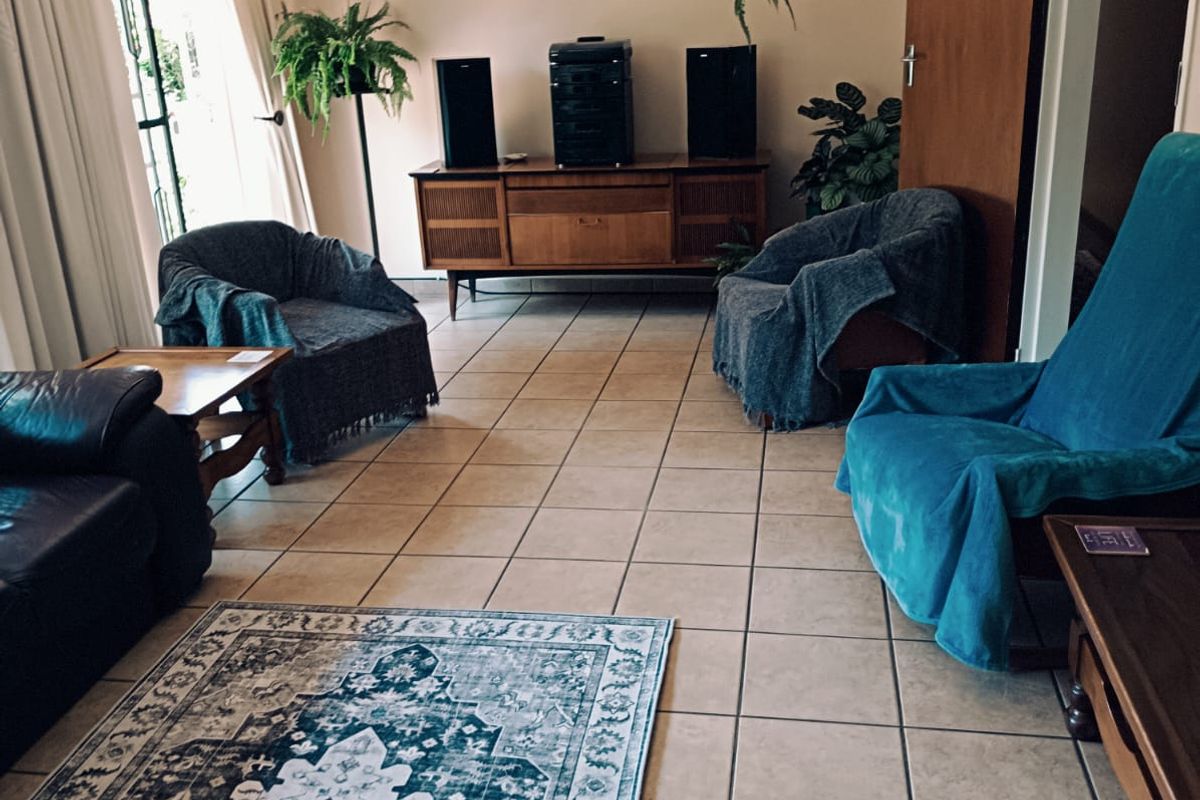 A living room featuring tiled flooring and a sliding glass door providing natural light.