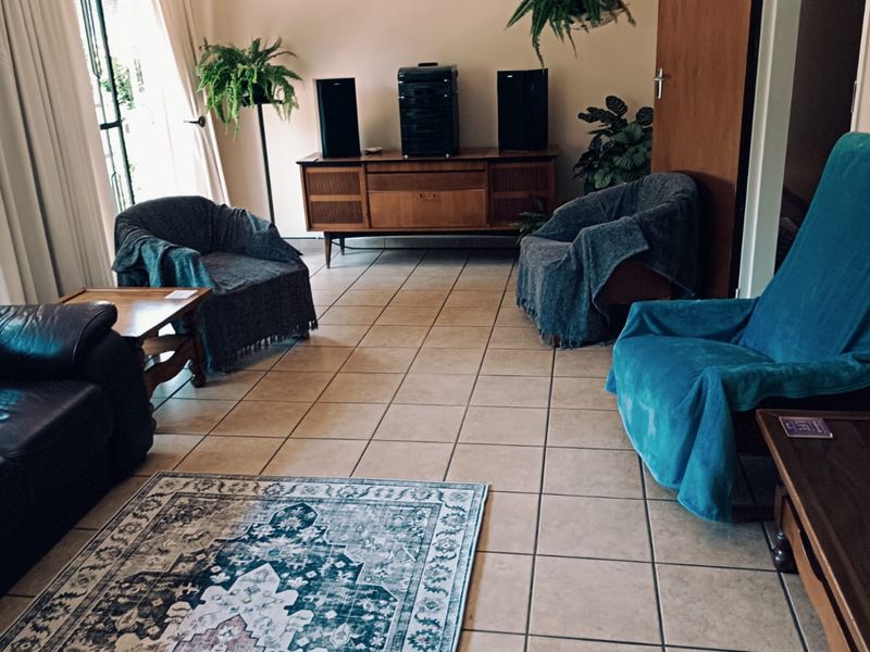 A living room featuring tiled flooring and a sliding glass door providing natural light.