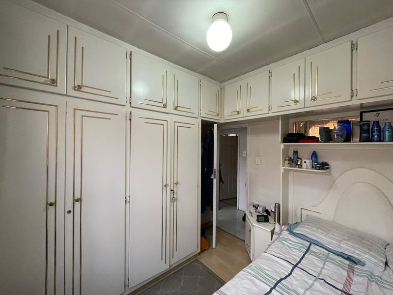 Bedroom featuring extensive white built-in cupboards with gold trim and overhead storage units, providing ample integrated storage space.
