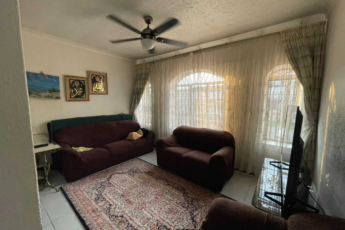 A comfortable living room featuring tiled flooring, a ceiling fan, and large arched windows with natural light.