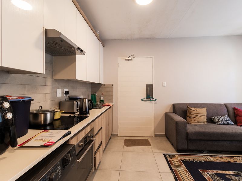 Open-plan kitchen and living area featuring modern cabinetry, built-in appliances, tiled flooring, and a neutral color palette.