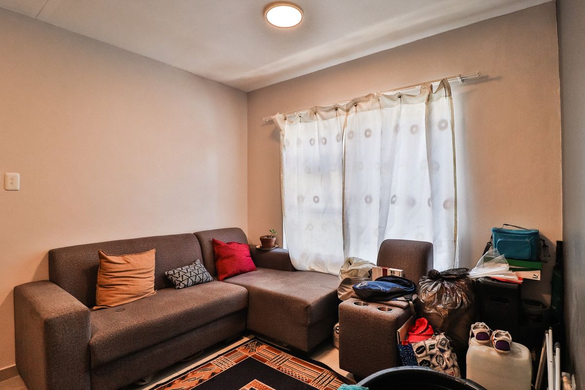 A living room space featuring neutral wall finishes and a window with an installed curtain rod.