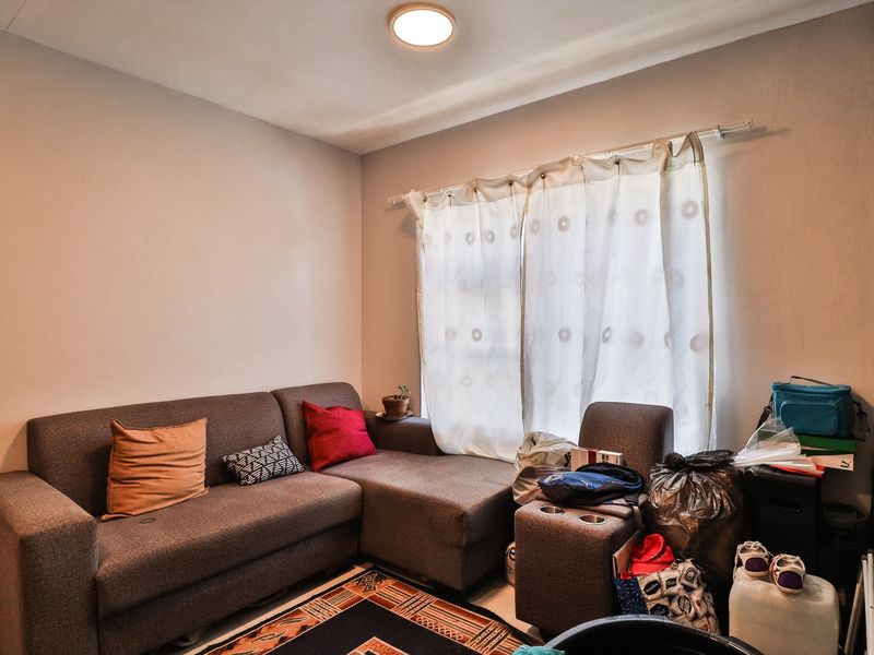 A living room space featuring neutral wall finishes and a window with an installed curtain rod.