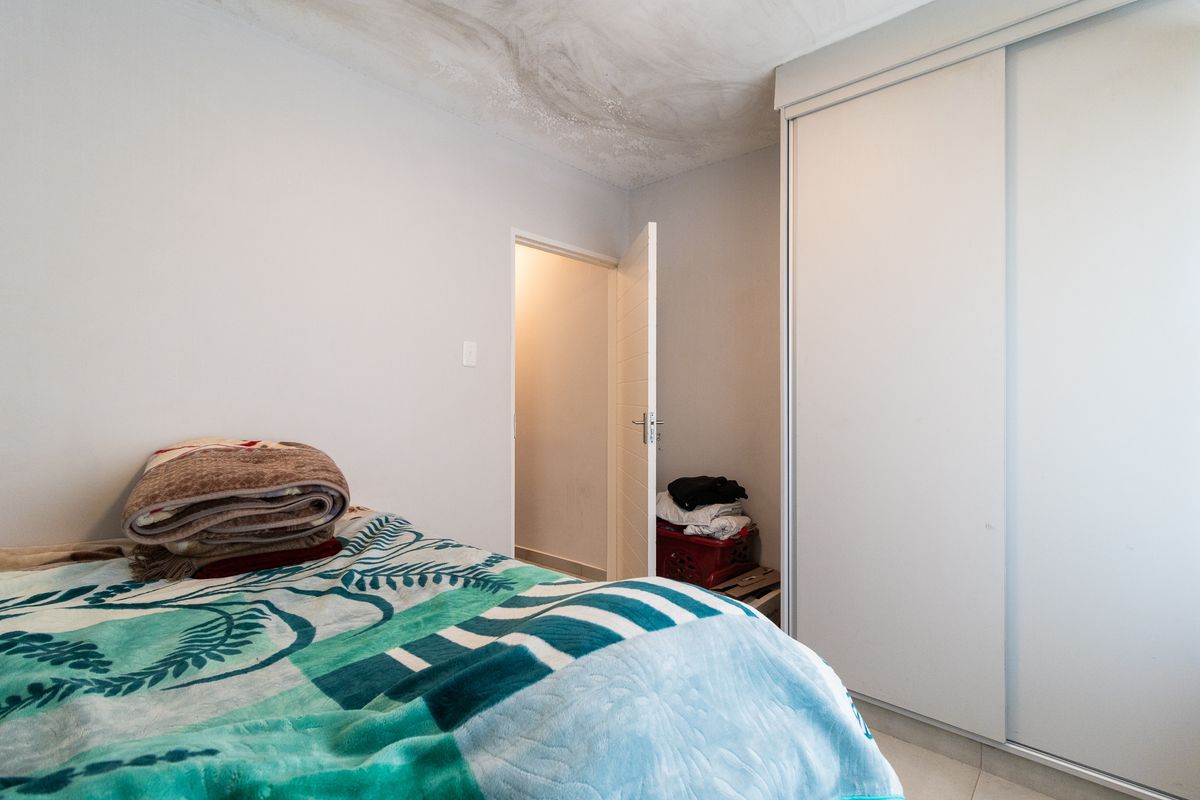 A bedroom featuring a built-in sliding door wardrobe and tiled flooring, currently showing signs of ceiling water damage and paint deterioration.