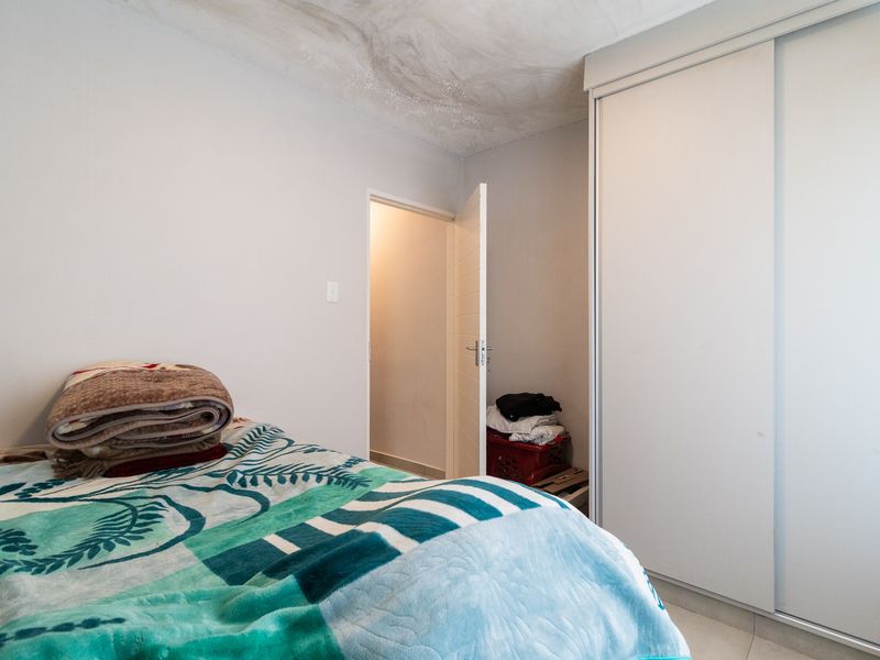 A bedroom featuring a built-in sliding door wardrobe and tiled flooring, currently showing signs of ceiling water damage and paint deterioration.