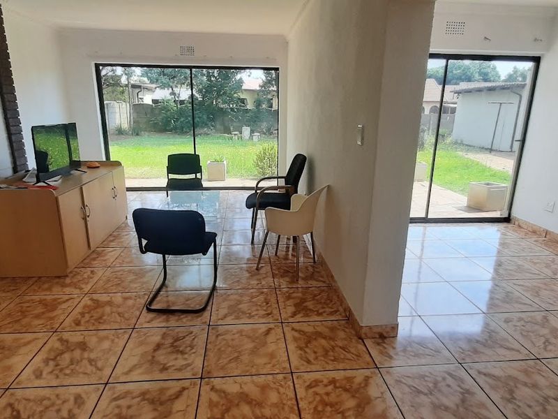 Spacious living area featuring ceramic floor tiles, a brick fireplace, and large sliding glass doors providing direct access to the rear garden.