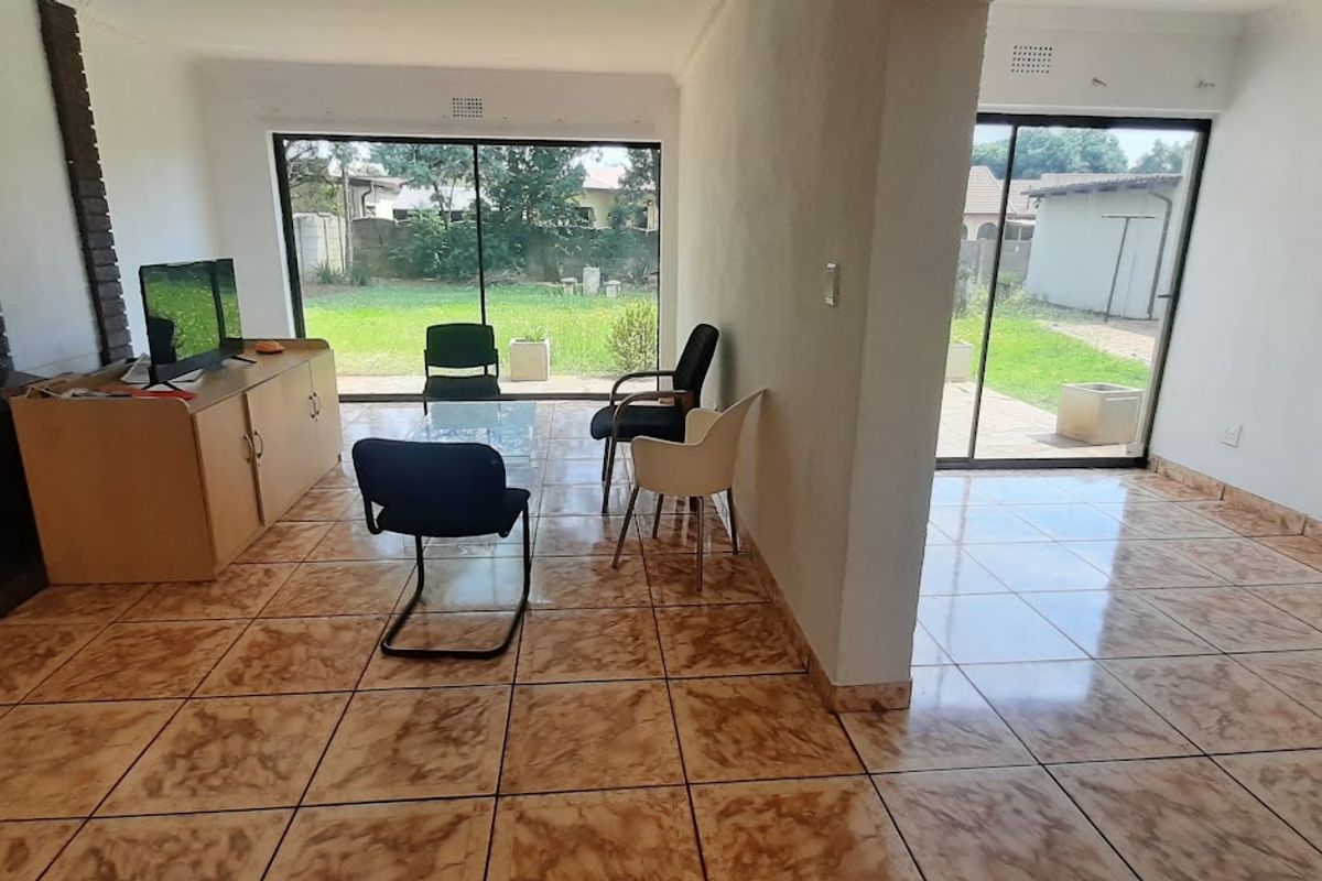Spacious living area featuring ceramic floor tiles, a brick fireplace, and large sliding glass doors providing direct access to the rear garden.