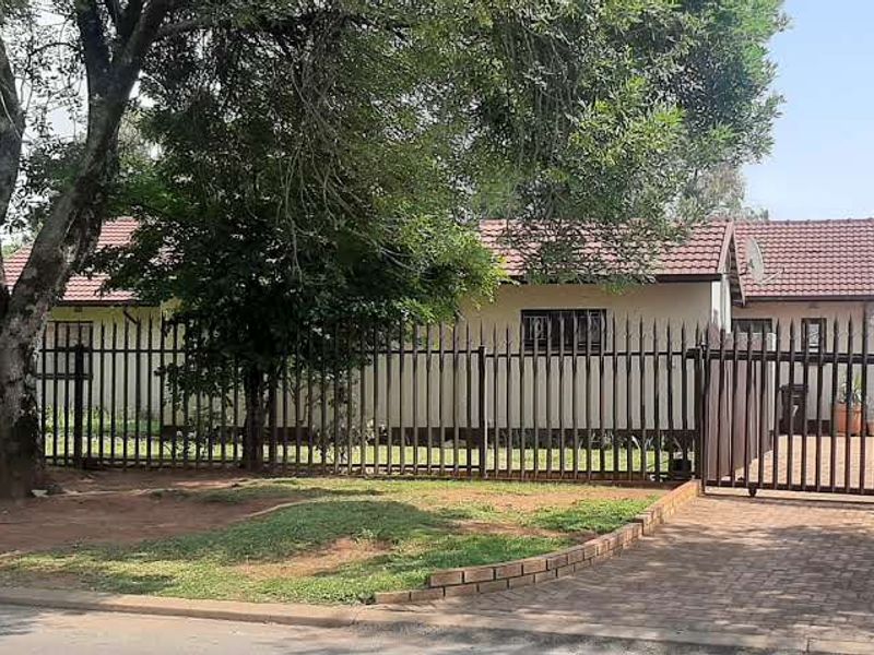 Front view of the property featuring a paved driveway, secure steel fencing, and a tiled roof house exterior.