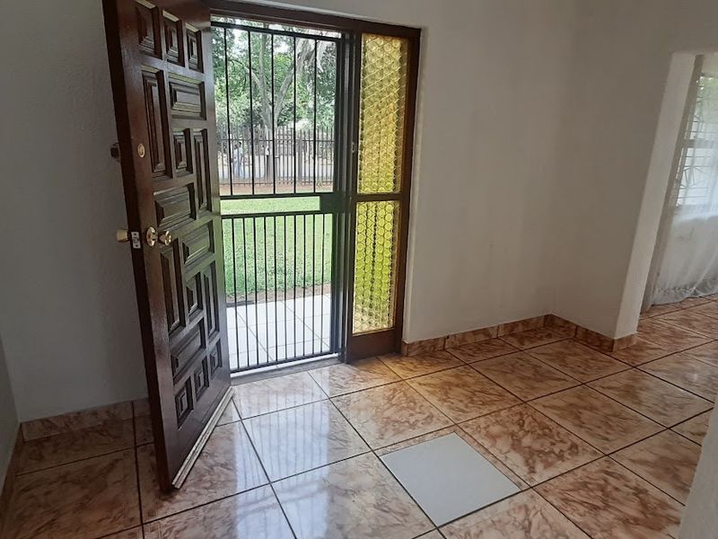 Entrance area featuring tiled flooring, a solid wooden front door, and a security gate leading to the exterior.