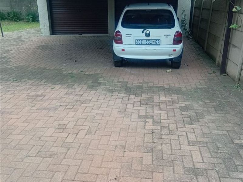 A double carport with roll-up garage doors and a paved driveway area.