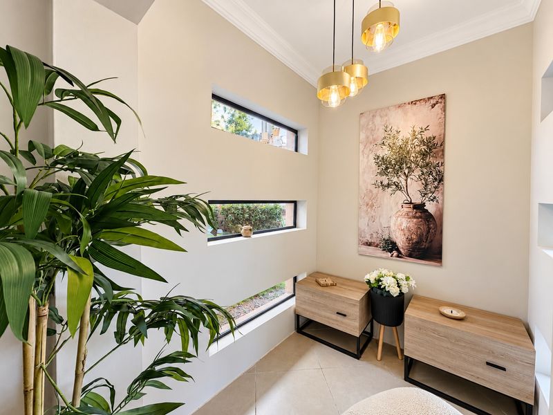 A bright and modern entryway featuring stacked horizontal windows, elegant pendant lighting, and neutral tiled flooring.
