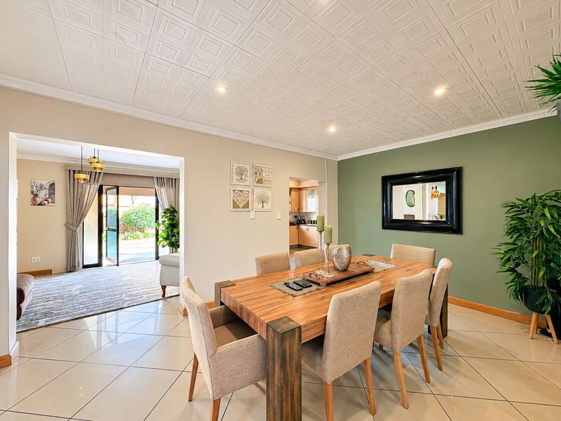 Spacious dining room featuring tiled flooring, a decorative textured ceiling, and an accent wall, with an open-plan flow to the adjacent living area and kitchen.
