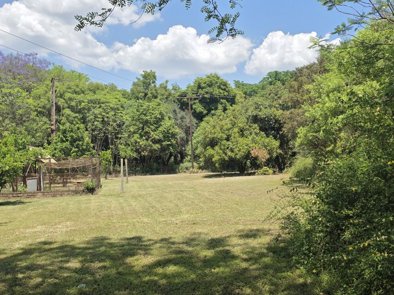 A spacious, well-established garden area featuring mature trees, expansive lawn, and a fenced enclosure, offering a peaceful outdoor setting.