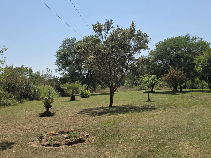 A spacious, established garden area featuring mature trees and open lawn space, typical of a small holding property.