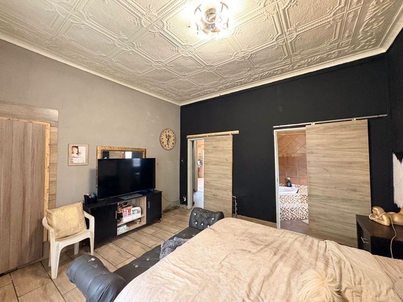 Spacious bedroom featuring a decorative pressed metal ceiling, tiled flooring, and modern sliding barn doors providing access to an en-suite bathroom.